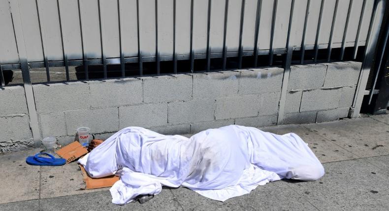 A homeless person' sleeping under a sheet on a sidewalk in Los Angeles, California on August 22, 2019, home to one of the nation's largest homeless populations
