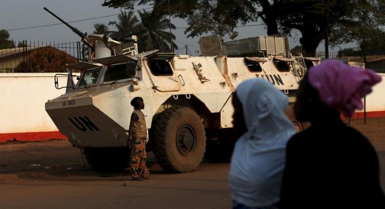 Women walk by a United Nations peacekeeping armoured vehicle guarding the outer perimeter of a compound of a school used as an electoral centre at the end of the presidential and legislative elections, in the mostly muslim PK5 neighbourhood of Bangui, Central African Republic, February 14, 2016. 