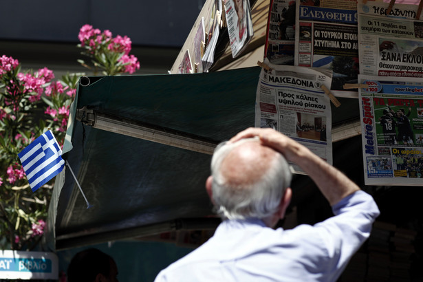 Mężczyzna patrzy na nagłówki gazet w Atenach