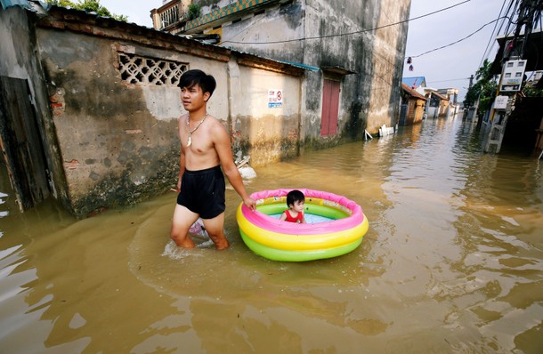 A man pulls his daughter on a flooded village after heavy rainfall caused by tropical storm Son Tinh