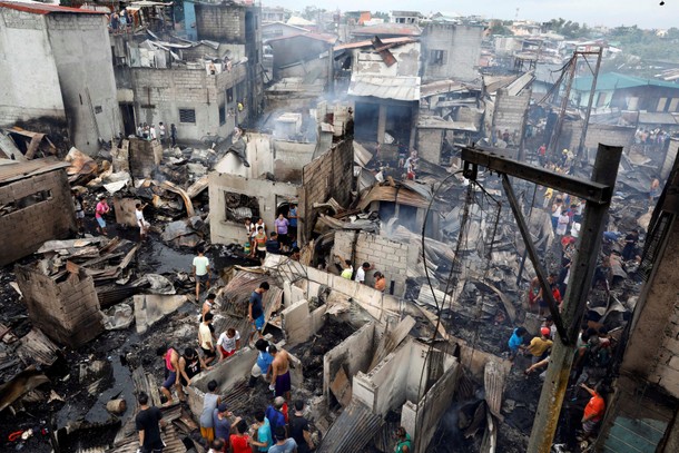 Fire victims gather on the ruins of houses after a fire razed a residential neighbourhood in Malabon