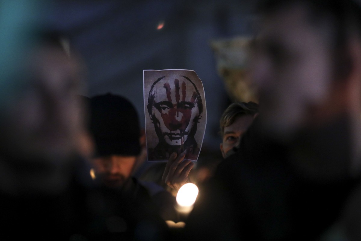 Demonstrators hold placards, featuring images of Russia's President Vladimir Putin, during a candlelit march to show support for people of Ukraine, from the town hall to the Colosseum, in Rome, Italy, on Friday, Feb. 25, 2022. Around the world, people gathered in groups that numbered from the dozens to the thousands to express support for the people of Ukraine. Photographer: Alessia Pierdomenico/Bloomberg