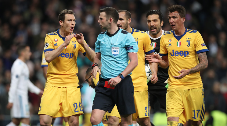 Michael Oliver a reklamáló Juve-játékosok gyűrűjében /Fotó: AFP