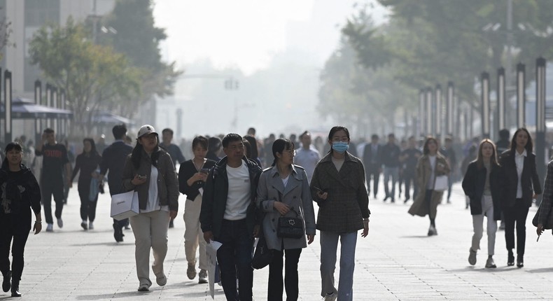 People walk along a business street in Beijing.WANG ZHAO/Getty Images