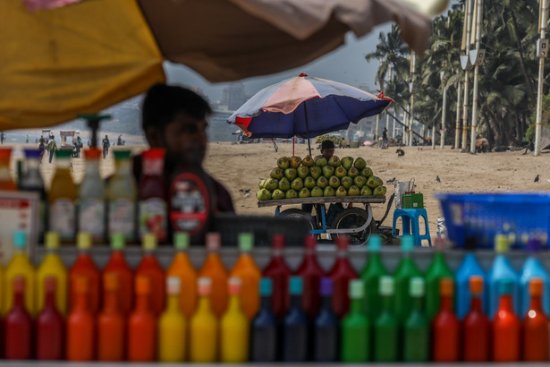 Sprzedawcy używają dużych parasoli, aby uniknąć fali upałów w upalne popołudnie na plaży Juhu w Bombaju, Indie
