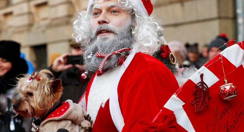 A man dressed as Santa Claus holds a dog as he takes part in the charity Santa Fun Run in Riga