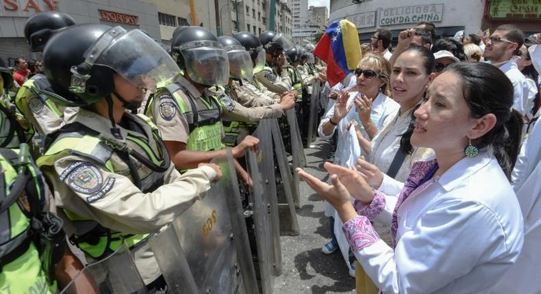 Doctors chant slogans in front of a line of National Guard personnel in riot gear during a demonstration against the shortage in medicines and in rejection of the government of President Nicolas Maduro, in Caracas on May 17, 2017