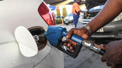A pump attendant fills a car with fuel.
