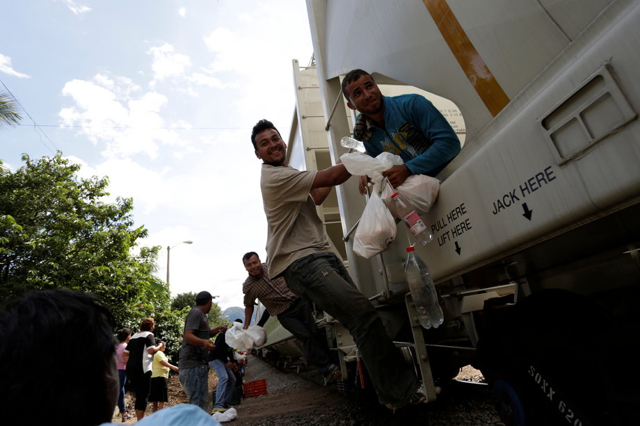 Volunteers from a group called "Las Patronas" (The bosses), a charitable organization that feeds Central American immigrants who travel atop a freight train known as "La Bestia," pass food and water to immigrants on their way to the US border, in Veracruz, Mexico, October 22, 2016.