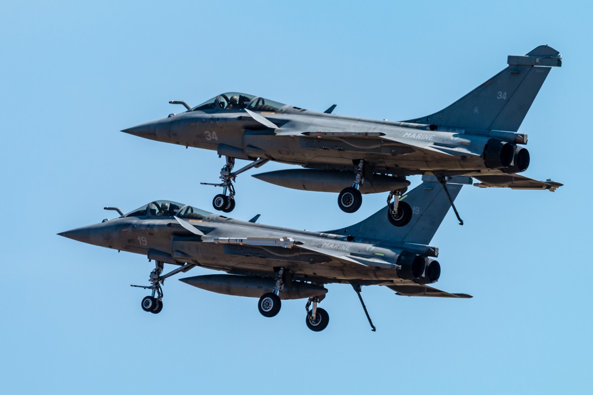 Dwa francuskie myśliwce Rafale w locie, lecące równolegle na tle błękitnego nieba.