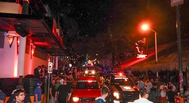 People look on as firefighters and police patrol the Blue Parrot nightclub in Playa del Carmen, Mexico where 5 people were killed, including three foreigners, during a music festival on January 16, 2017