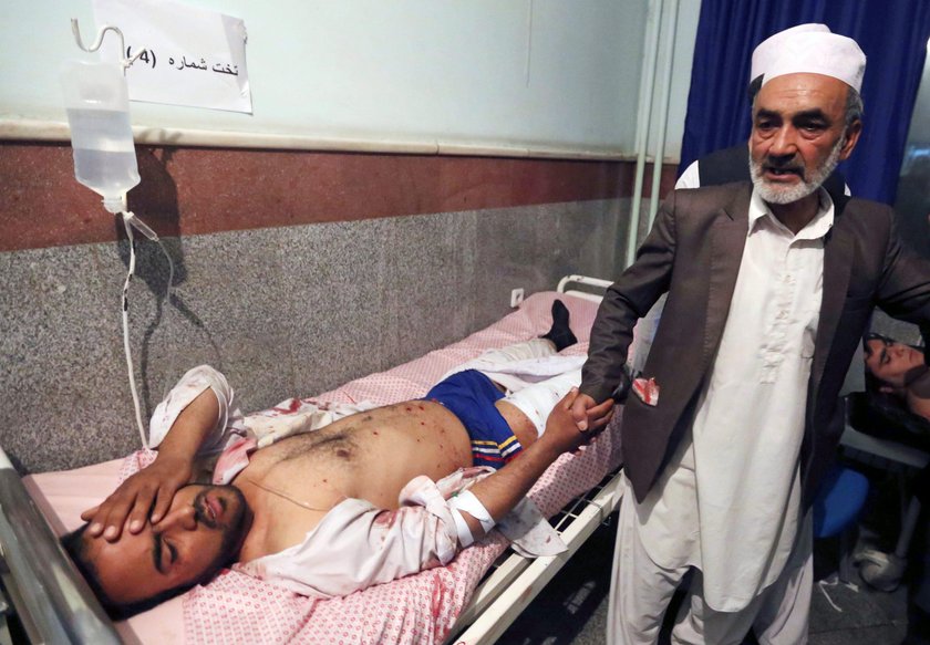 Afghan policemen and relatives inspect at the site of a suicide attack in Herat, Afghanistan