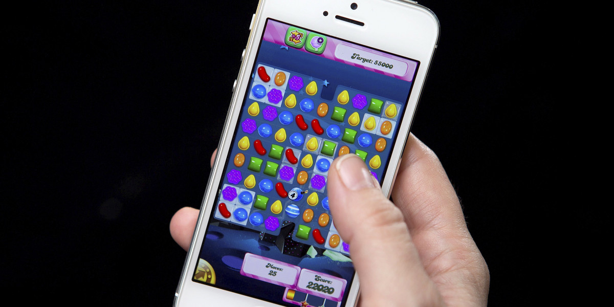 A woman poses in a file photo illustration with an iPhone as she plays Candy Crush in New York
