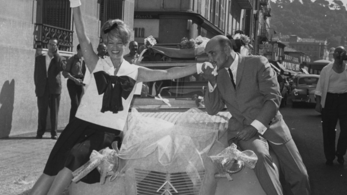 Actress Janis Paige being kissed on the hand by her new husband, lyricist Ray Gilbert, as the two sit on the bonnet of their 'Just Married' car, outside the church on their wedding day in France, 1962.