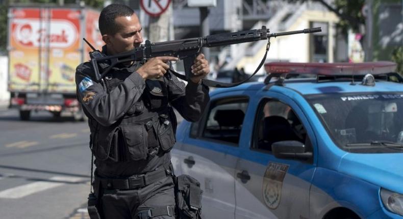 A militarized police officer aims his assault rifle during a search and capture operation at the Mangueira shanty town in Rio de Janeiro, after a policeman there was shot dead