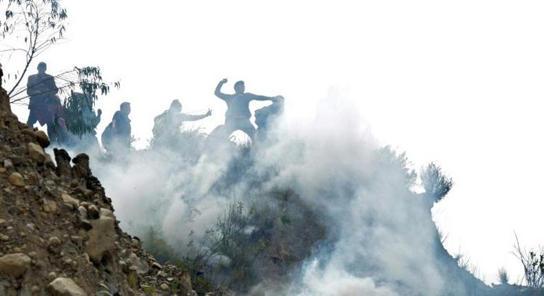 Bolivian coca growers from Los Yungas region confront riot police agents within a tear gas cloud, during a protest against a bill that caps legal coca crops extensions in La Paz on February 21, 2017