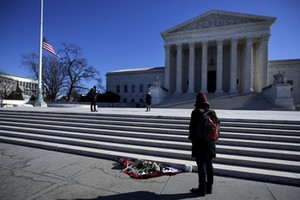 Flowers are seen as a woman stands in front of the Supreme Court building in Washington D.C. after t