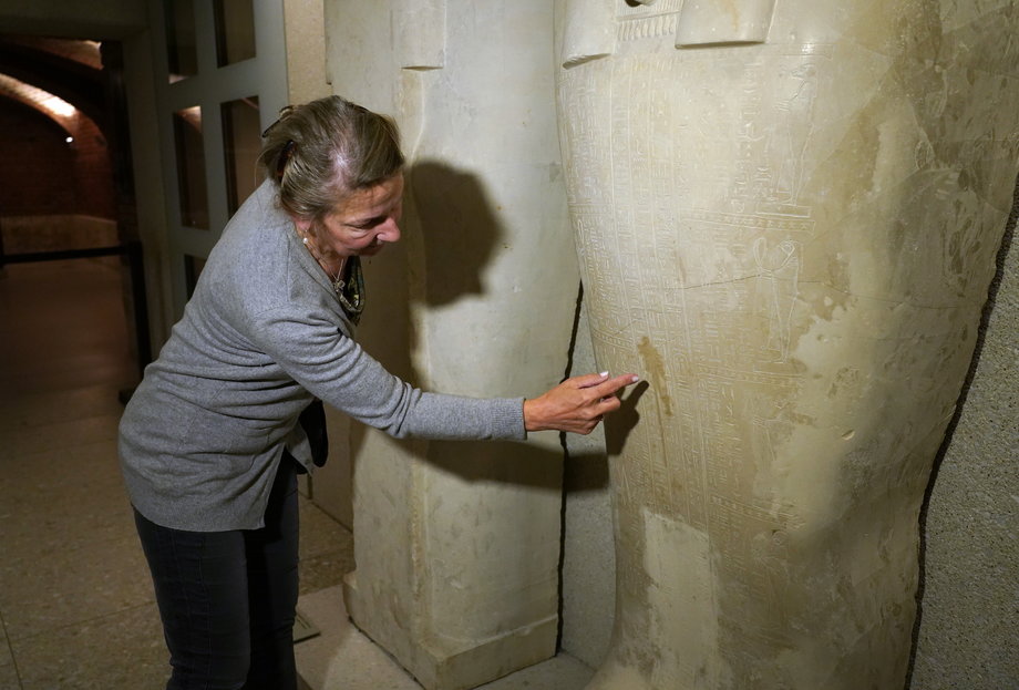 Dyrektorka Muzeum Egipskiego i Kolekcji Papirusów wskazuje na oleistą plamę pozostawioną przez wandala na pokrywie starożytnego egipskiego kamiennego sarkofagu. W podobny sposób zniszczono 63 inne obiekty.