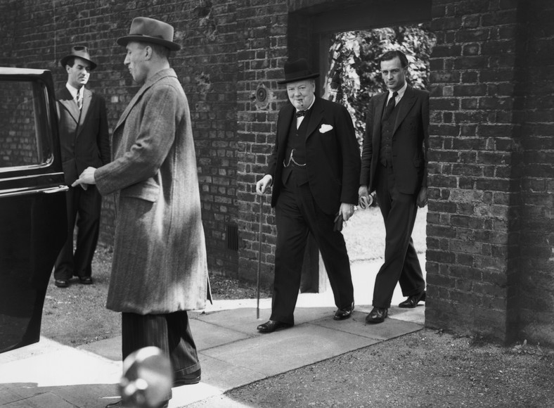 Winston Churchill (z laską) w drodze do parlamentu w dniu zakończenia działań wojennych w Europie, maj 1945 r. Zdjęcie wykonane przy tylnej bramie kancelarii premiera przy Downing St., którą wyszedł premier, by ominąć wiwatujące tłumy