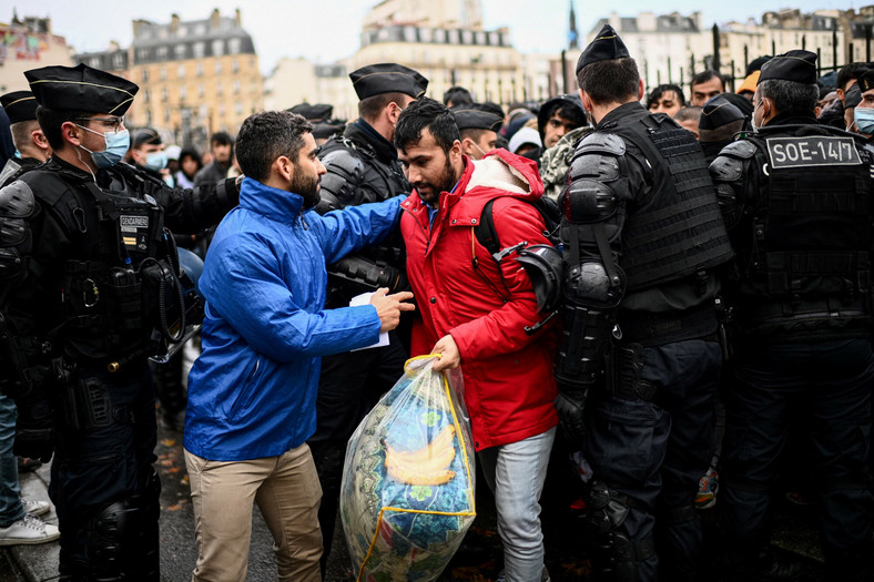 Migranci stojący w kolejce do autobusów, aby uzyskać tymczasowe schronienie podczas ewakuacji prowizorycznego obozu, w którym zgromadziły się setki osób, głównie Afgańczyków, Paryż, 17 listopada 2022 r.