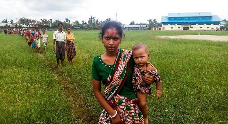 A woman holds a child in her arms as she arrives at Yathae Taung township in Rakhine state after fleeing violence in their home village