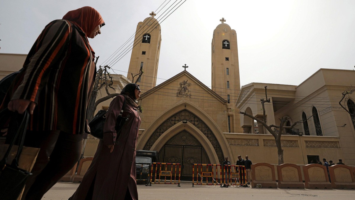 Women pass by the Coptic church that was bombed on Sunday in Tanta