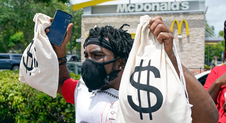 A McDonald's worker holds up bags to bring attention to the companies profits as he takes part in a 15-city walkout to demand $15hr wages Wednesday, May 19, 2021, in Sanford, Fla. (AP Photo/John Raoux)
