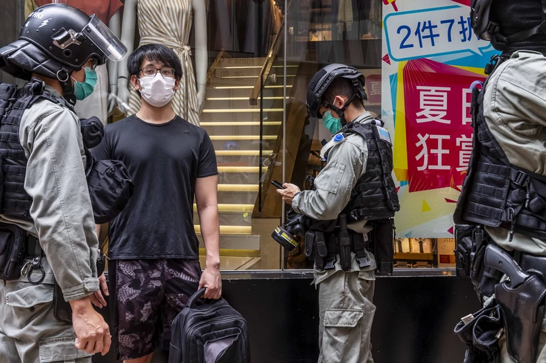 Młodzież protestująca na Causeway Bay w Hongkongu zatrzymana przez funkcjonariuszy policji. Młody chłopak jest przepytywany