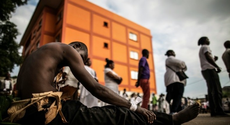 A man traditionally dressed with banana leaves joins mourners paying their respects at an improvised altar for those who perished during the post electoral violence in Libreville on September 6, 2016