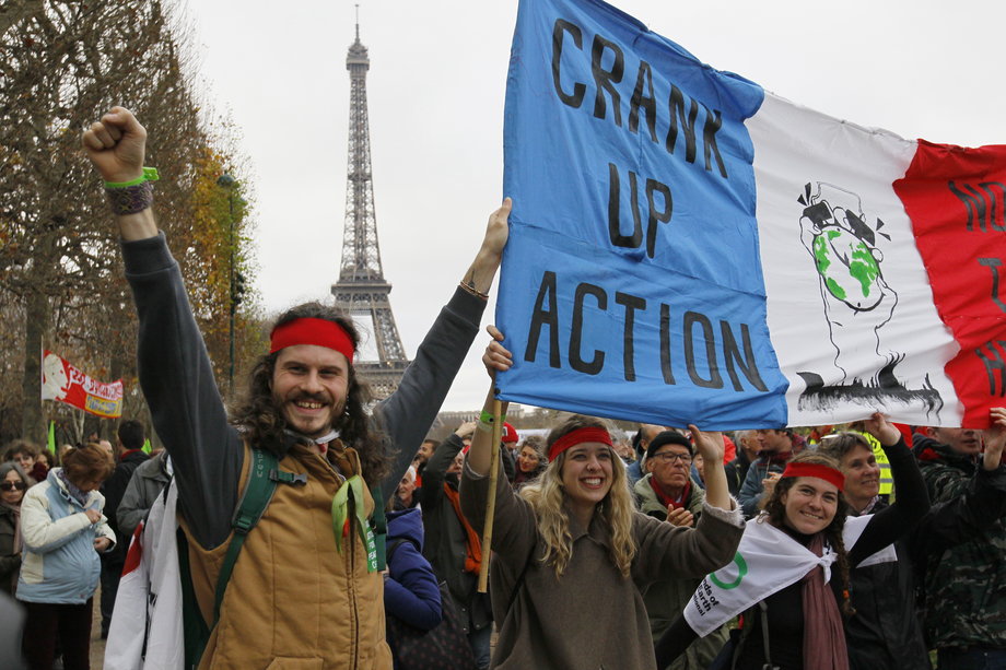 Environmentalists hold a banner reading, "Crank up the Action" at a demonstration near the Eiffel Tower, as the World Climate Change Conference 2015 (COP21) continues near the Le Bourget, near Paris, December 12, 2015.