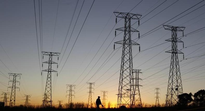 A man walks past electricity pylons as he returns from work in Soweto, outside Johannesburg May 15, 2012. REUTERS/Siphiwe Sibeko