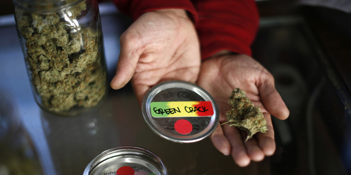 A volunteer displays jars of dried cannabis buds at the La Brea Collective medical marijuana dispensary in Los Angeles, California, March 18, 2014.