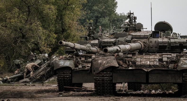 Ukrainian soldiers (L) scavenge an abandoned Russian T-90A tank in Kyrylivka, in the recently retaken area near Kharkiv, on September 30, 2022.YASUYOSHI CHIBA/AFP via Getty Images