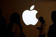 FILE PHOTO: A man looks at the screen of his mobile phone in front of an Apple logo outside its store in Shanghai