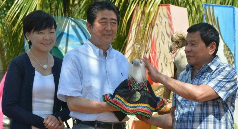 Japanese Prime Minister Shinzo Abe (2nd L) is handed a stuffed Philippine eagle by Philippine President Rodrigo Duterte at a hotel in Davao City, Mindanao on January 13, 2017
