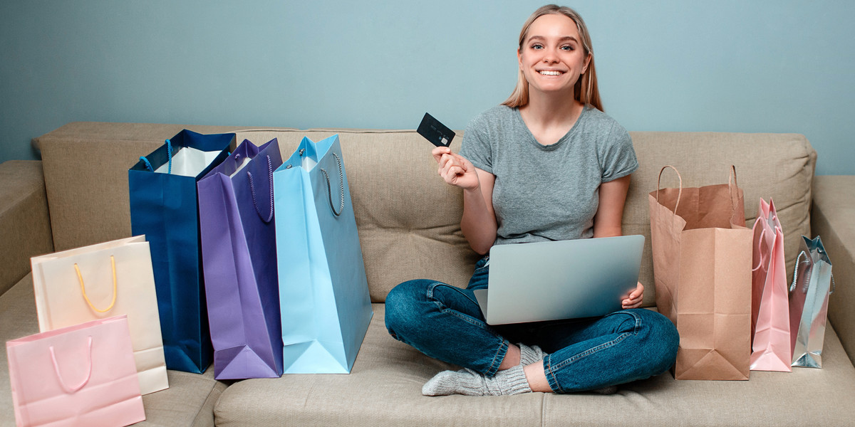 Online shopping at home. Young happy woman with credit card is ready to Singles day on a sofa near s