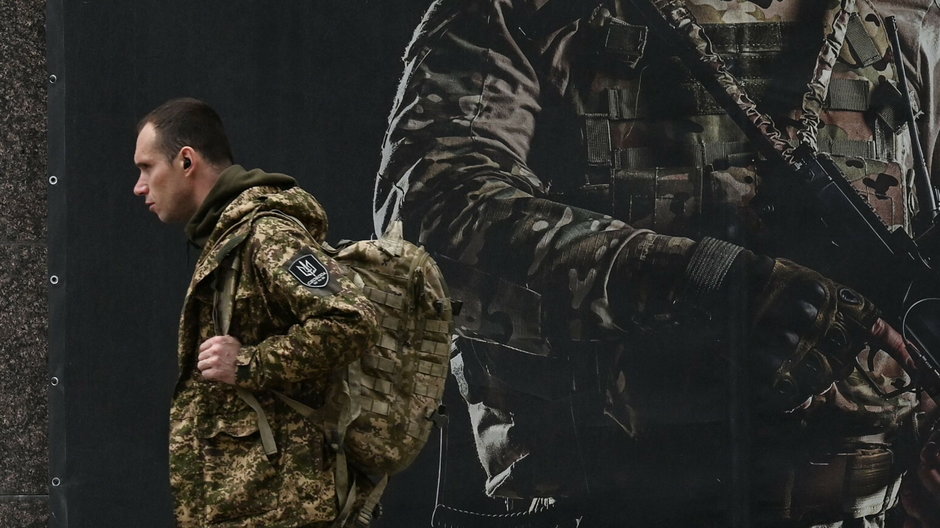 Ukraiński żołnierz przechodzi obok plakatu rekrutacyjnego w Kijowie, 23 kwietnia 2024 r.