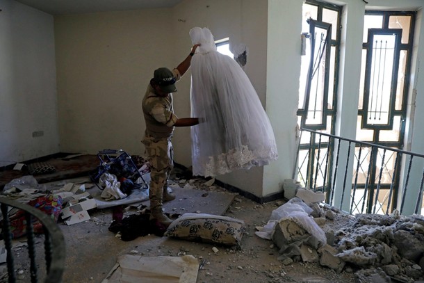 An Iraqi soldier holds up a wedding dress found at an abandoned house previously used by the Islamic