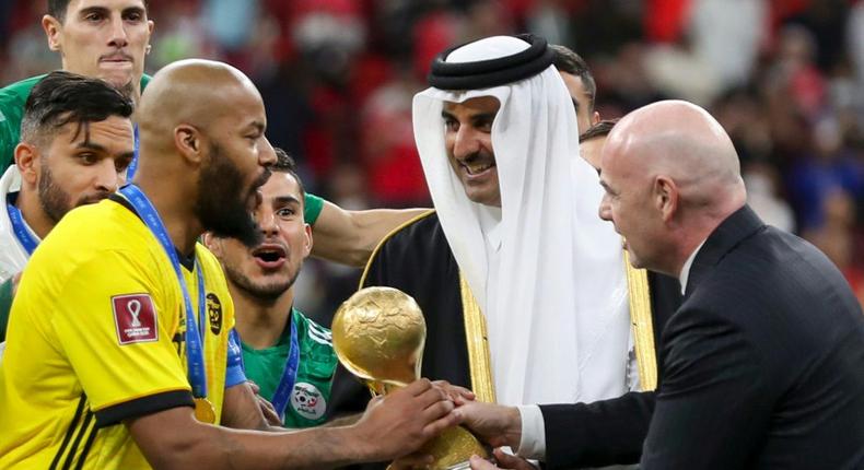 Qatar's Emir Sheikh Tamim bin Hamad al-Thani (C) and FIFA President Gianni Infantino (R) present Algeria's goalkeeper and captain Rais M'Bolhi with the the Arab Cup Creator: DENOUR