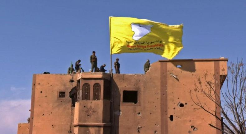 US-backed fighters of the Syrian Democratic Forces raise their flag in the Islamic State group's last redoubt of Baghouz as their commanders proclaim the total elimination of its caliphate