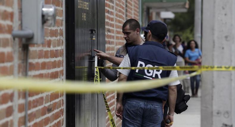 Federal agents inspect bullet impacts at a crime scene in Ocotlan, Mexico