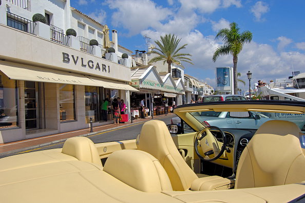 Luksusowy samochód i sklepy w ekskluzywnym porcie jachtowym w Puerto Banús, Marbella, Hiszpania.