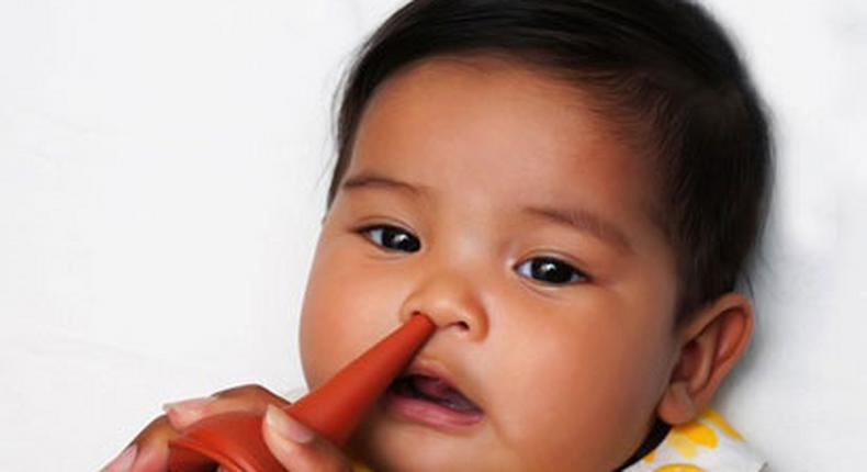 A baby's stuffed nose being relieved with bulb syringe