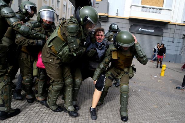 A demonstrator is detained during clashes with riot police at a students' march for a better educati