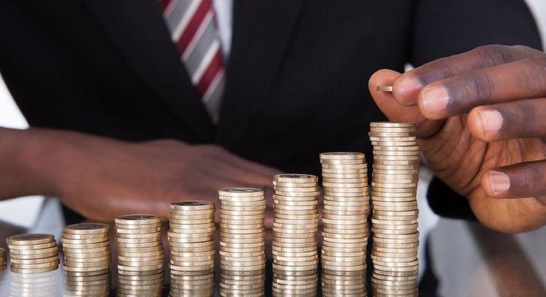 A man placing a gold coin on a line of ascending coin stacks