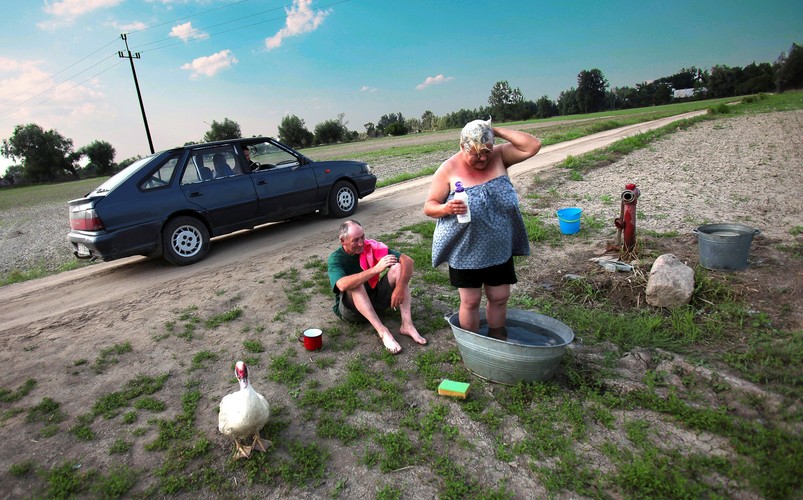 Danuta Pietrzak kąpie się w miednicy na szczerym polu. Dom Pani Danuty został zniszczony przez powódź, a zarazem została ona pozbawiona łazienki. Wiaczemin, 17 sierpnia 2010r., BZ WBK PressFoto 2011 Wyróżnienie 2 | Cywilizacja Katarzyna Mała Photoo