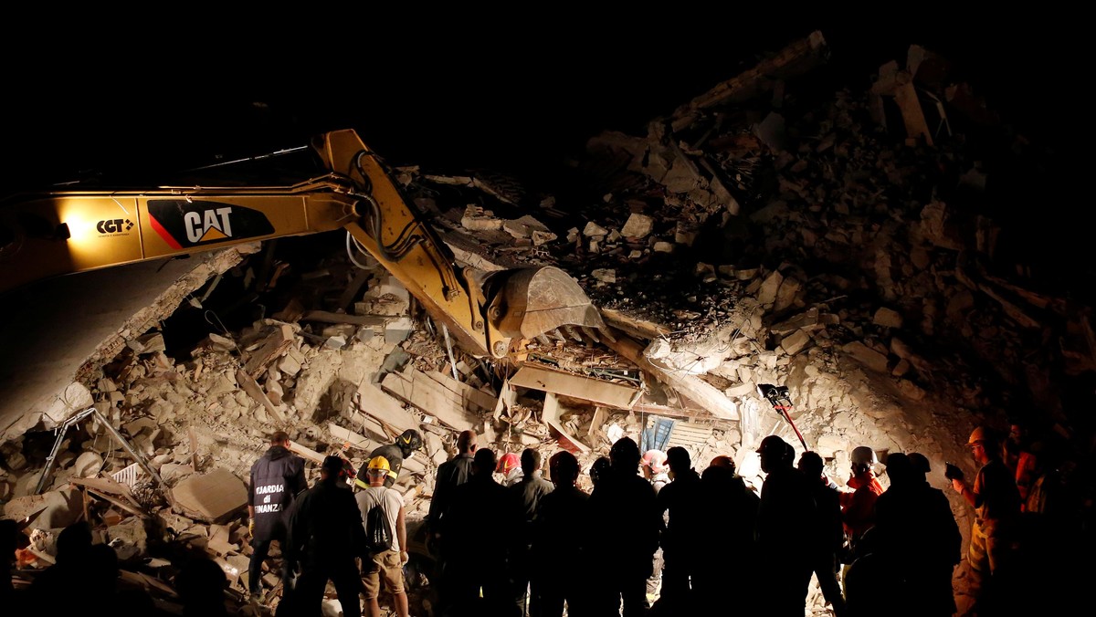 Rescuers work in the night at a collapsed house following an earthquake in Pescara del Tronto