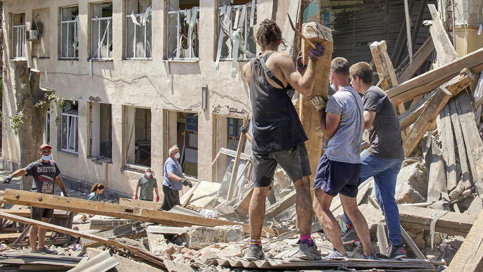 Mieszkańcy sprzątają zniszczenia w liceum, które zostało zbombardowane. Charków, 20 czerwca 2022 r.