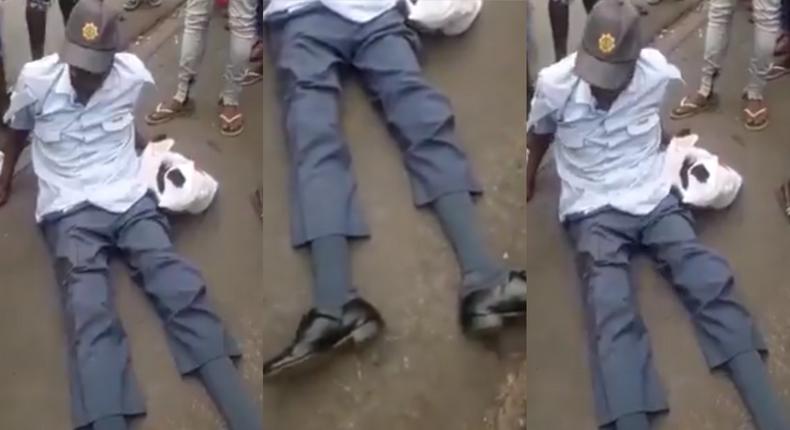 Crowd gather around drunk police officer as he is unable to rise up from the ground