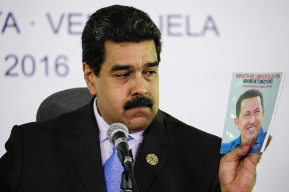 Venezuela's President Nicolas Maduro holds a book with a photo of Venezuela's late President Hugo Chavez, as he talks to the media during a news conference after the 17th Non-Aligned Summit in Porlamar, Venezuela, September 18, 2016.